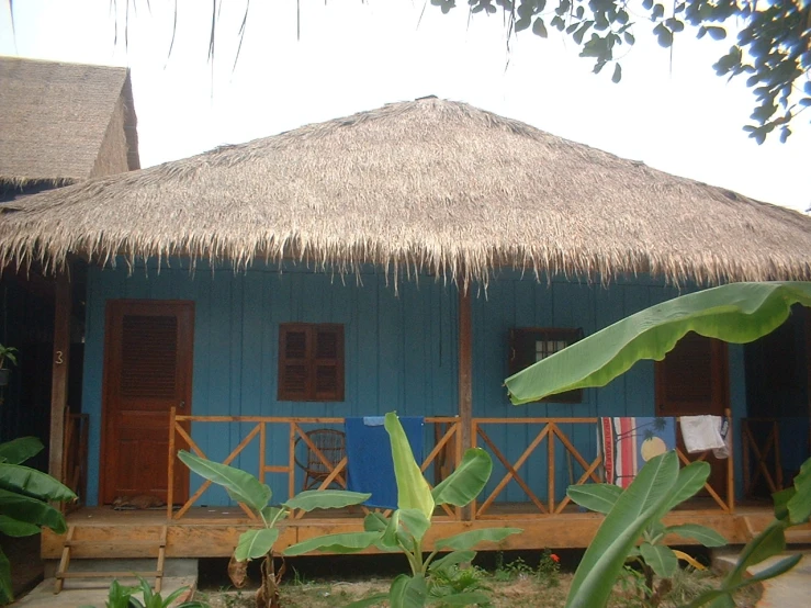 a blue building with thatched roof and a balcony