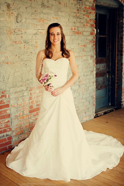 a woman standing in front of a wall in a white dress