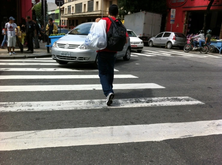 a man crosses the street in front of several parked cars