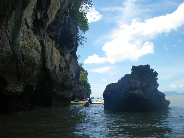 people are rowing a canoe towards a large rock formation