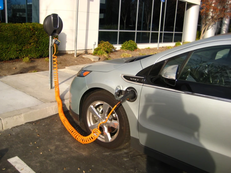 an electric car is plugged in and the driver will change the tire