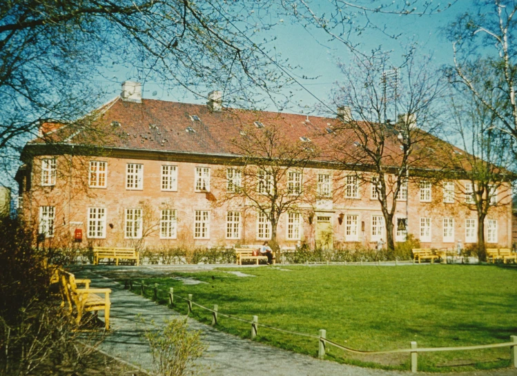 large brick building with trees and walkway next to lawn