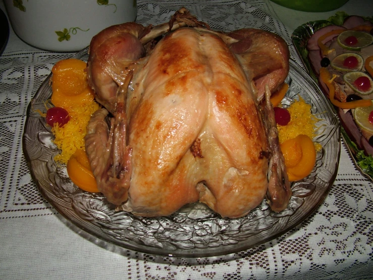 a cooked turkey sits in a plate with fruit