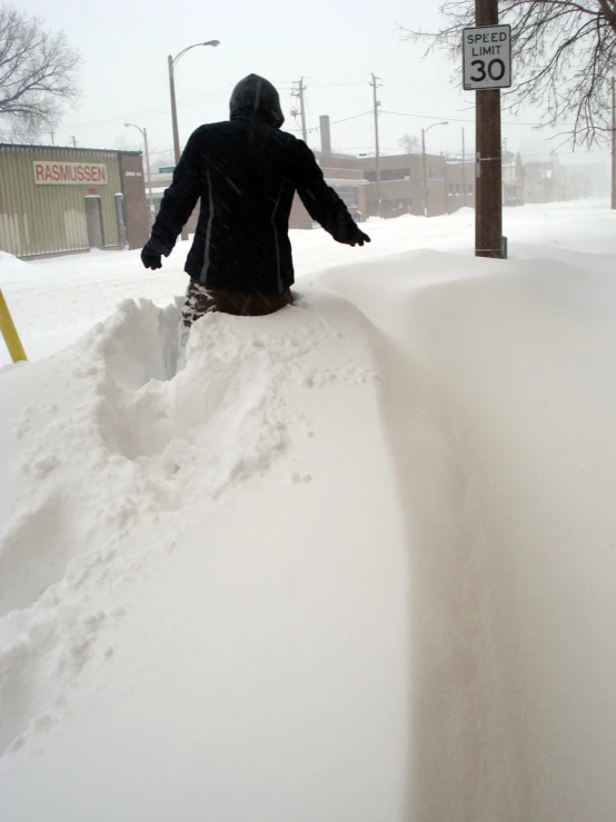 a man in a black jacket on the side of a road covered with snow