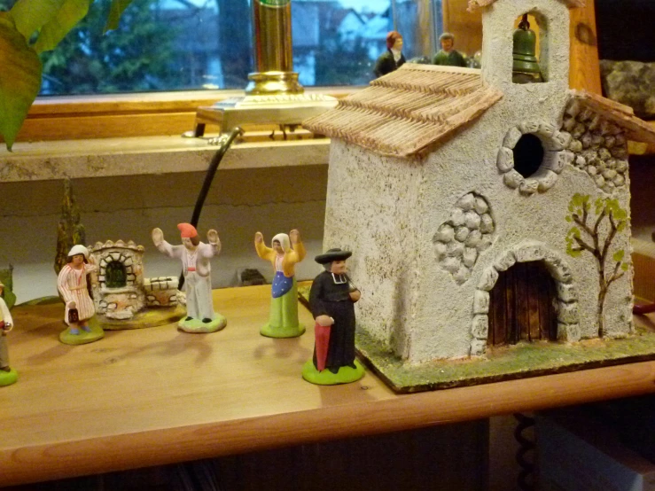 small village on wooden table with toy figurines and a lamp