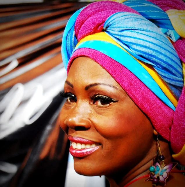 a women with a colorful turban smiles to the side