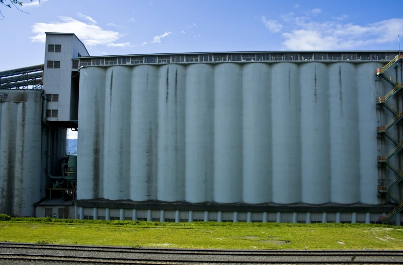 the large silos are beside a building with a blue sky