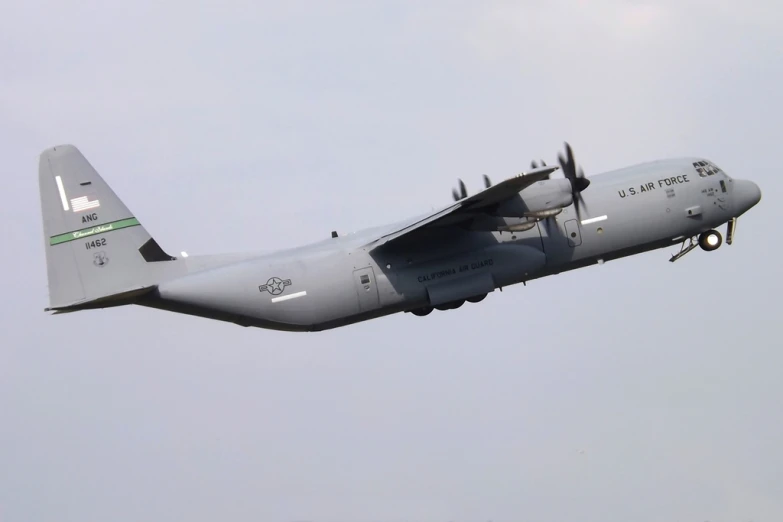 the large air force plane flies through the cloudy sky