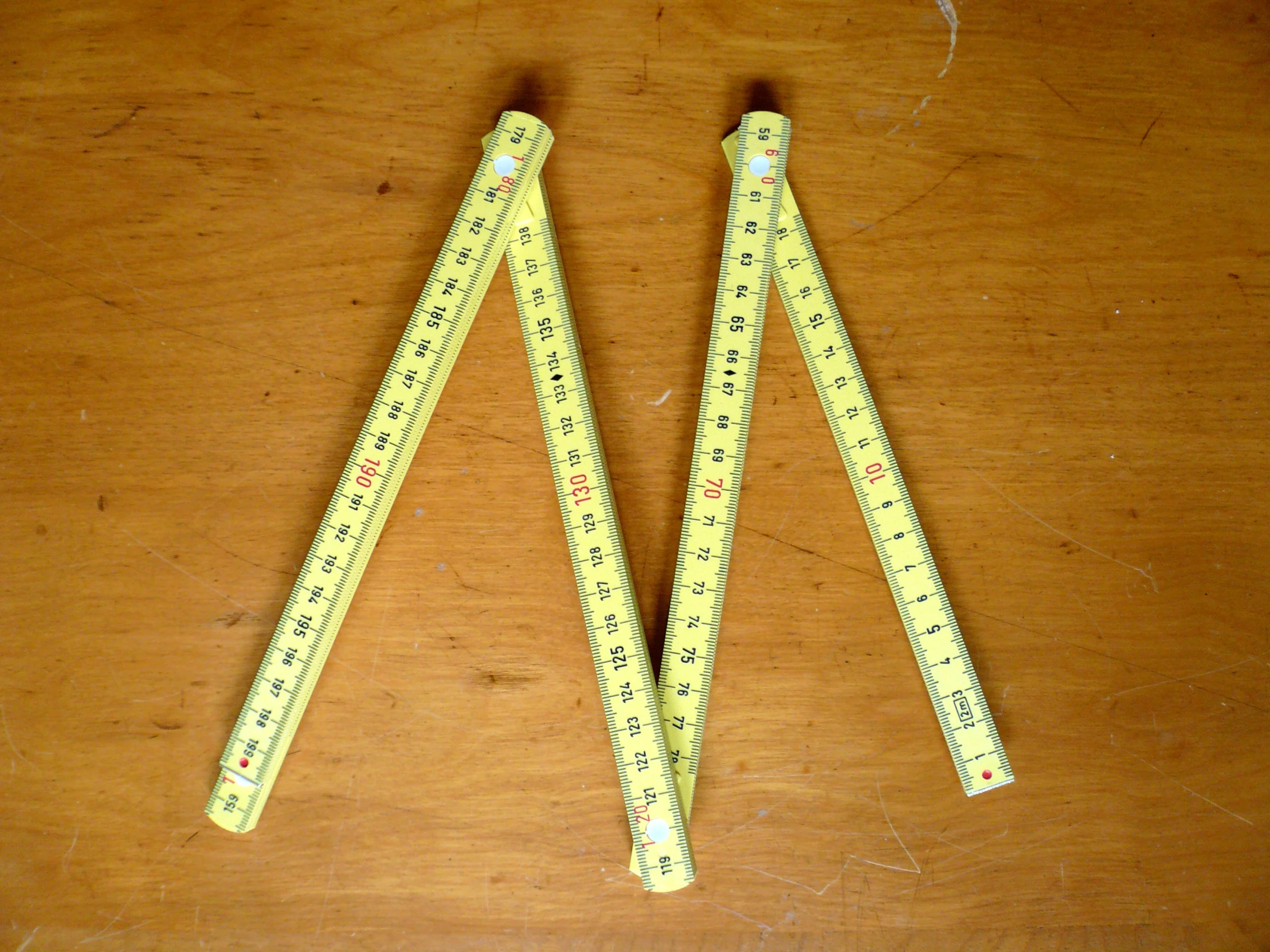 yellow measuring strips on wooden table near scissors