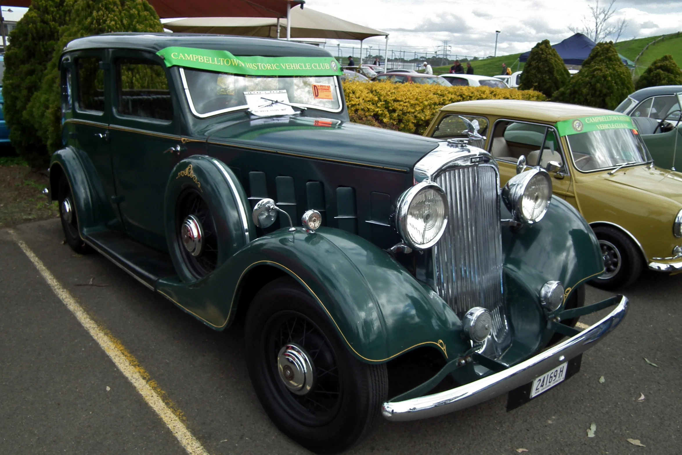 an old green car parked in a parking lot