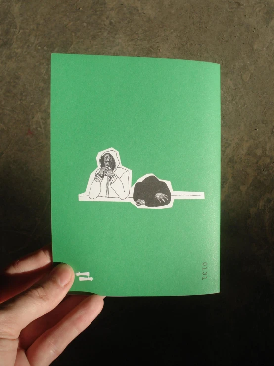 a person holding a book with a green cover and a black dog