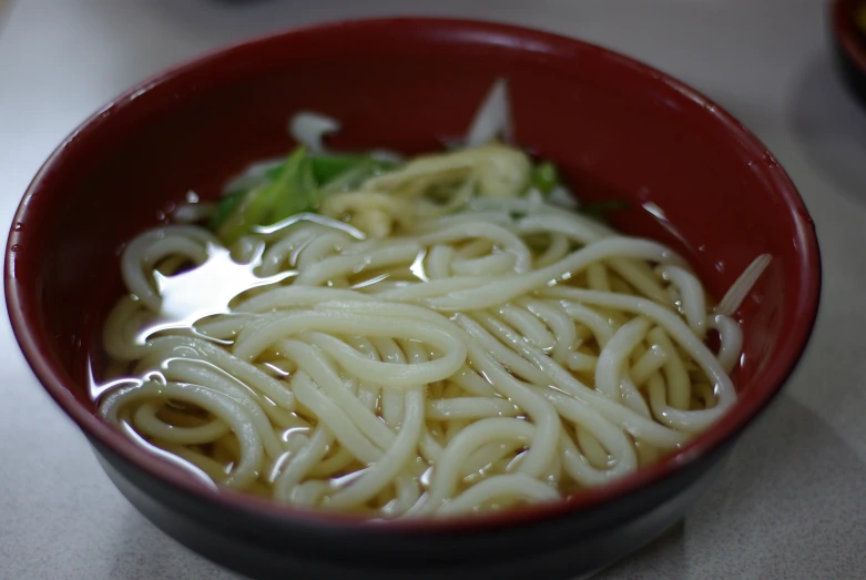 a bowl filled with noodles and broccoli on top of a counter