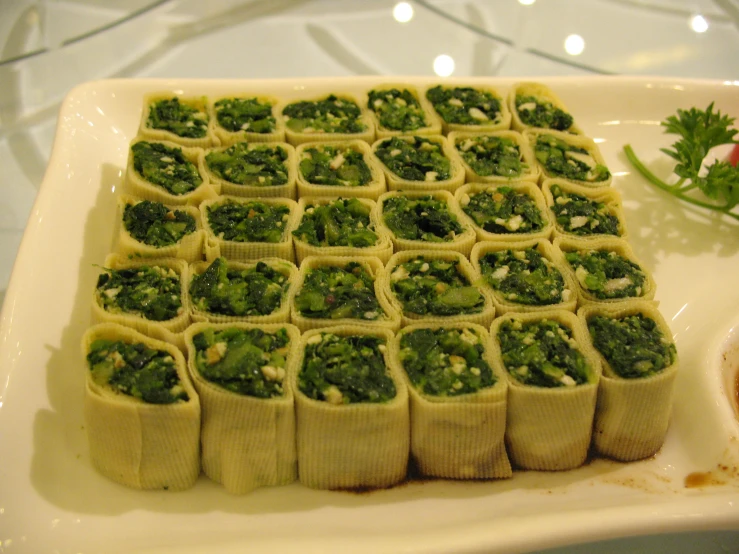 this square tray has a square pattern made of tiny pizzas with greens