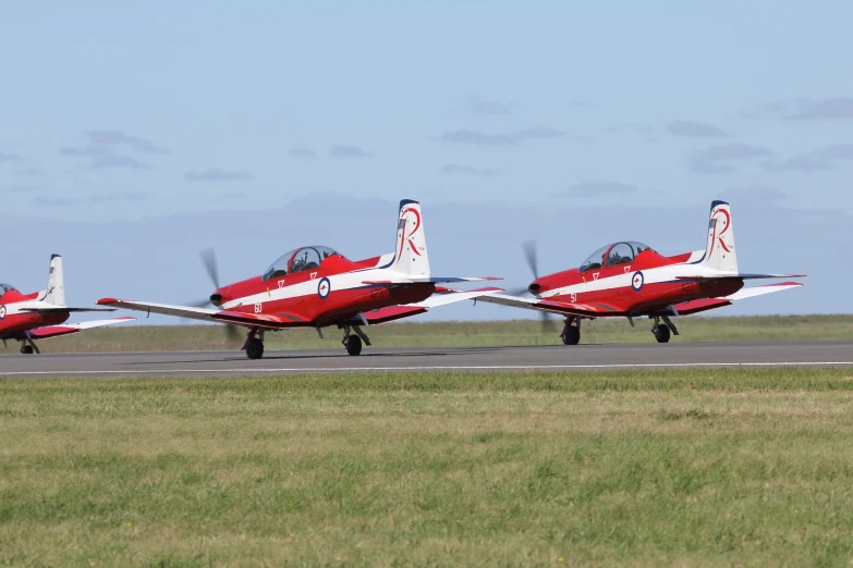 three red and white planes in position to takeoff