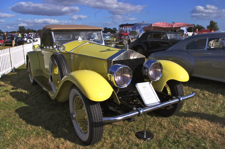 the yellow car is parked near other old cars