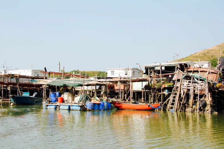 people and boats are sitting on the side of the river