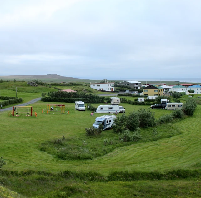 a big grassy field with some cars and buses parked on the grass