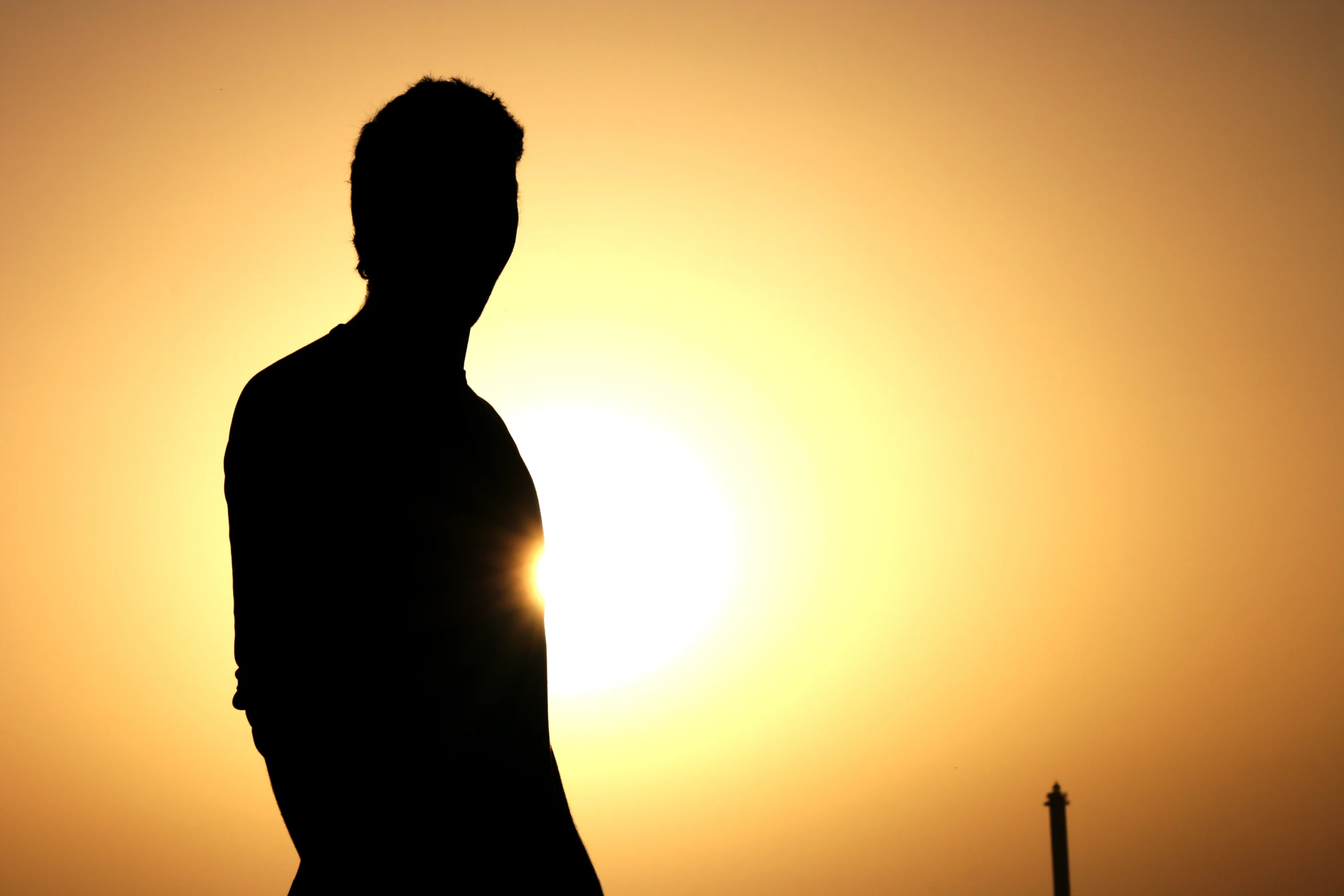 a person standing under a sun setting in the sky