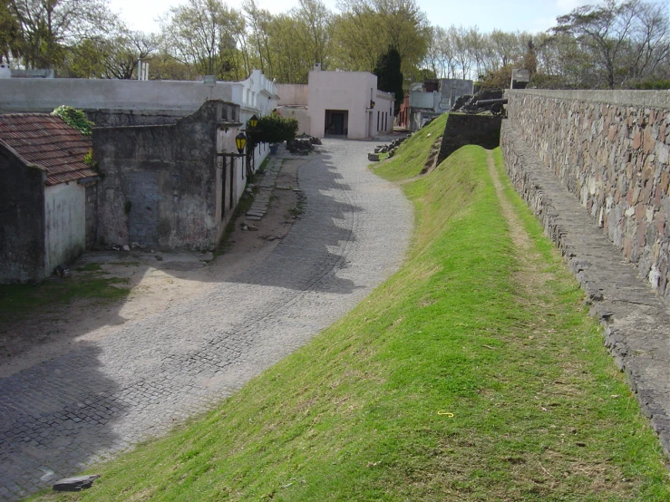 a stone walled road with building in the background