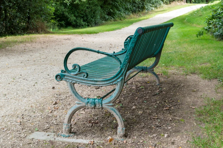 the green bench is left alone in the dirt