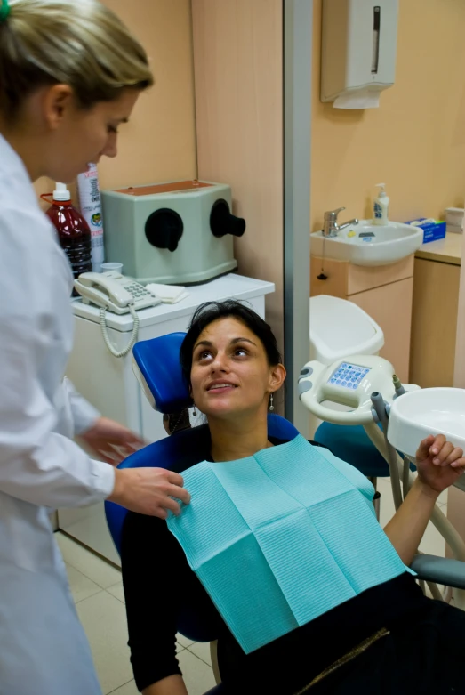 a woman is smiling at the dentist while holding onto soing