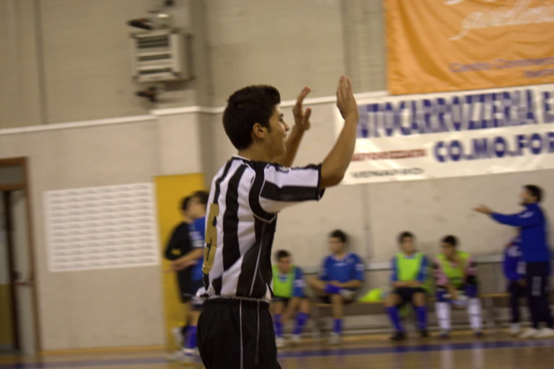 a young man trying to reach a ball in a gym