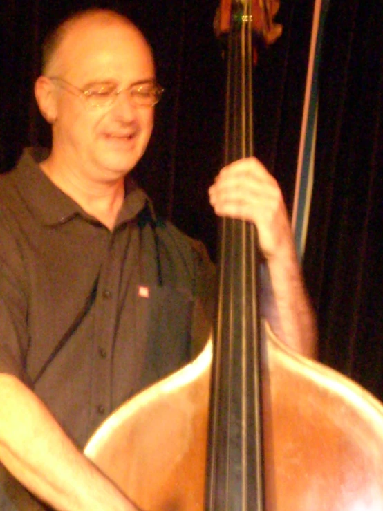 man playing cello for concert, wearing glasses and black shirt