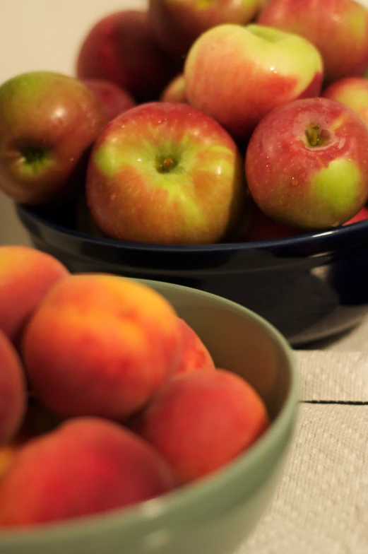 two bowl of peaches on a table and one has peaches