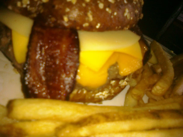 a cheeseburger, bacon, and fries sitting on a white plate