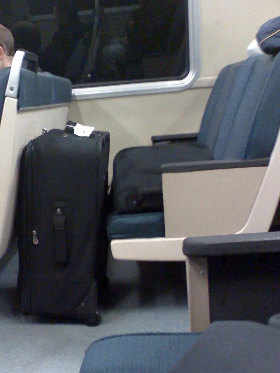 two black bags sit next to a male passenger in an airport