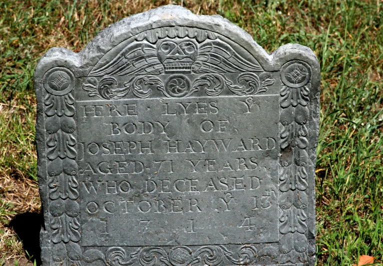 a grave marker sits in the grass on the lawn