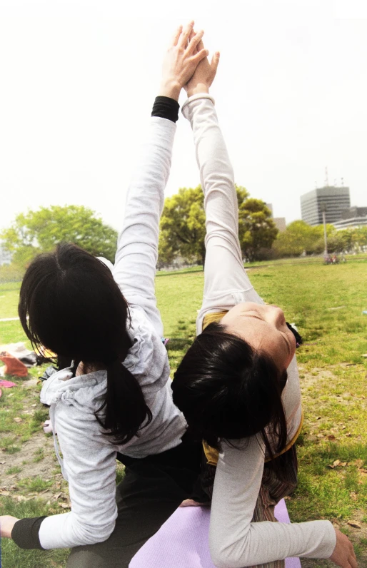 two girls are doing yoga in a park