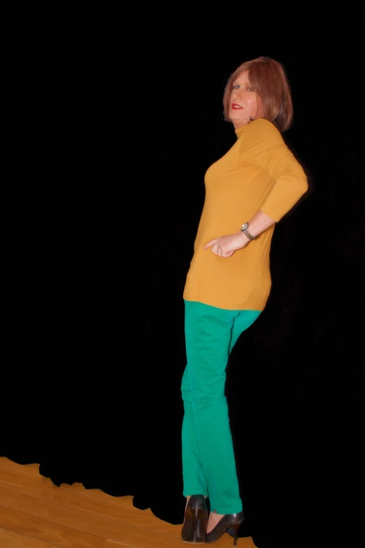 the woman is posing in the dark wearing some green pants