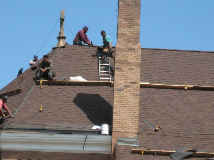 workers are on the roof of a brick building