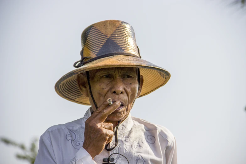 the older lady in the big hat is smoking soing