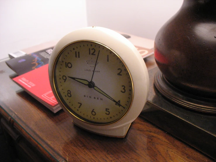 a close up of a small white clock on a desk