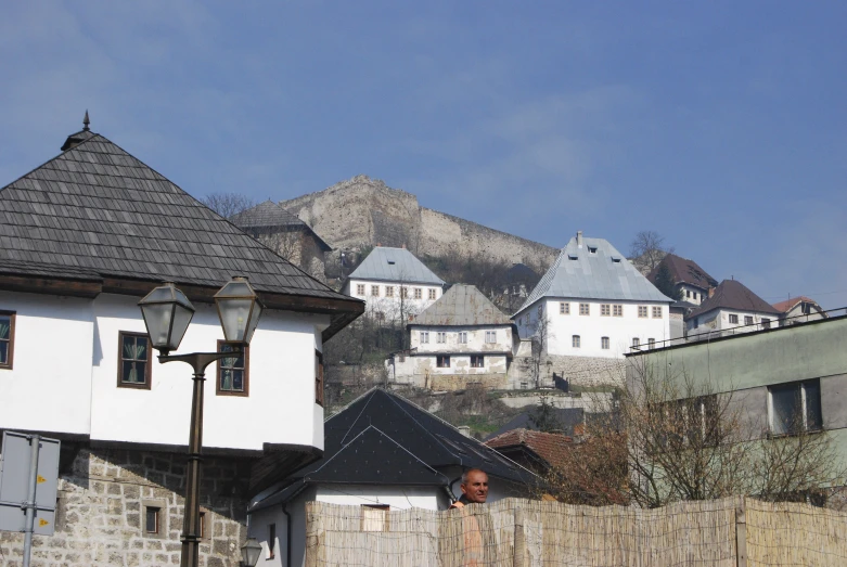 a man walks by the small old town with an old castle in the distance