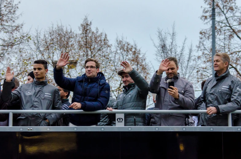 a crowd of people wearing jackets with their hands up