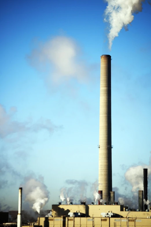 smoke billows from a large chimney in the sky