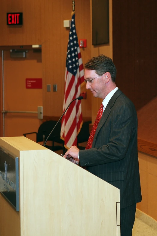 a man at a podium next to an american flag