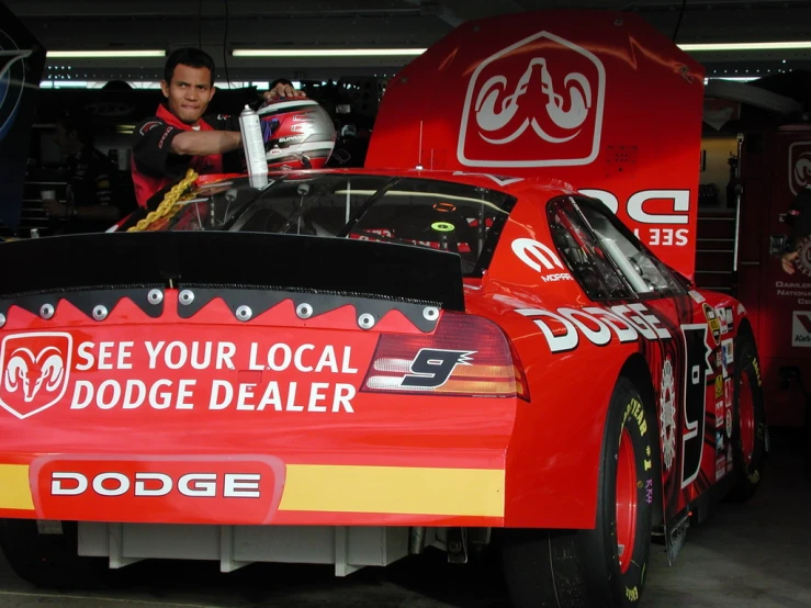 a man putting a tire changer on top of a red race car