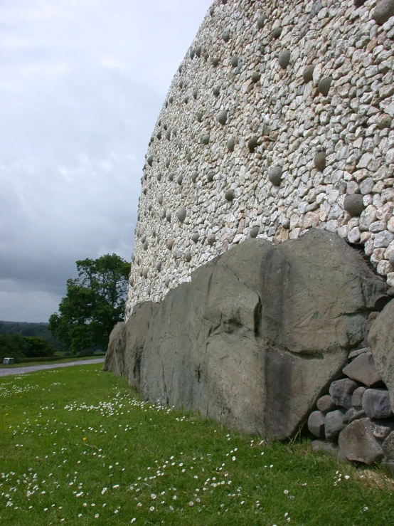 a stone rock wall made up of small rocks with grass in the foreground