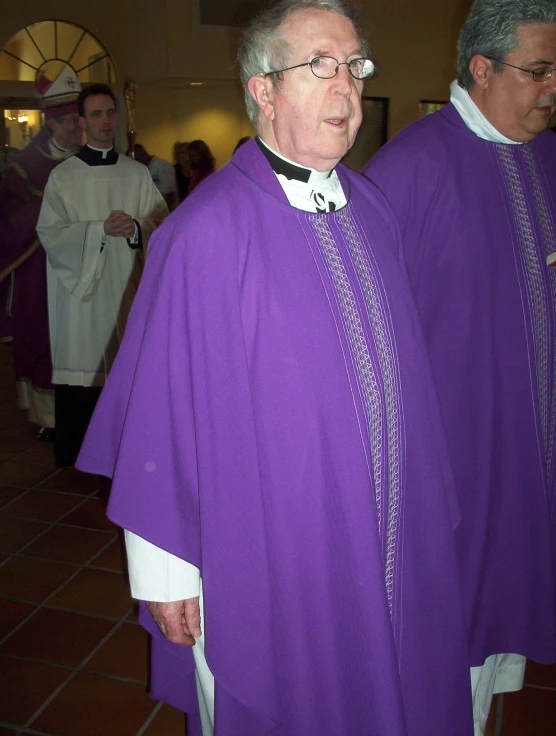 two priests are in purple attire one in black and the other in white