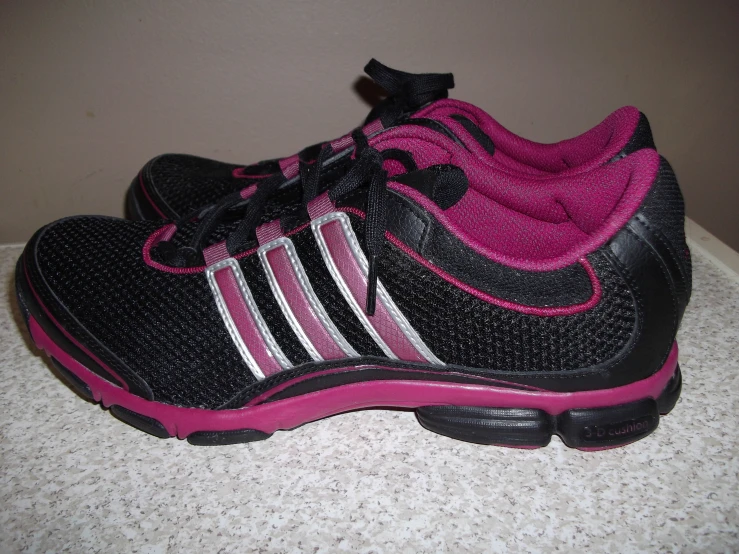 a black and pink shoe with pink soles