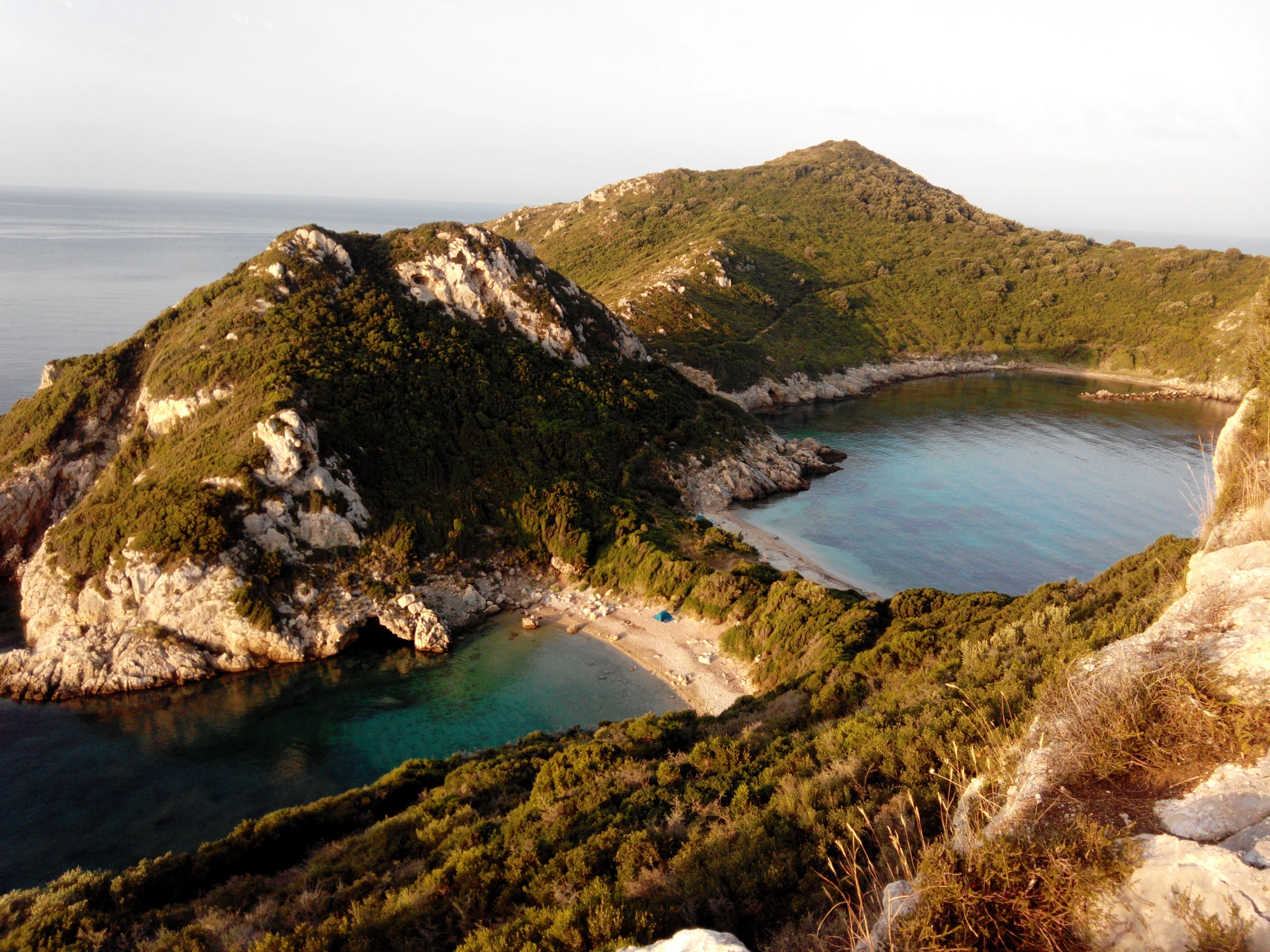 an island surrounded by water and hills on the other side of the shore