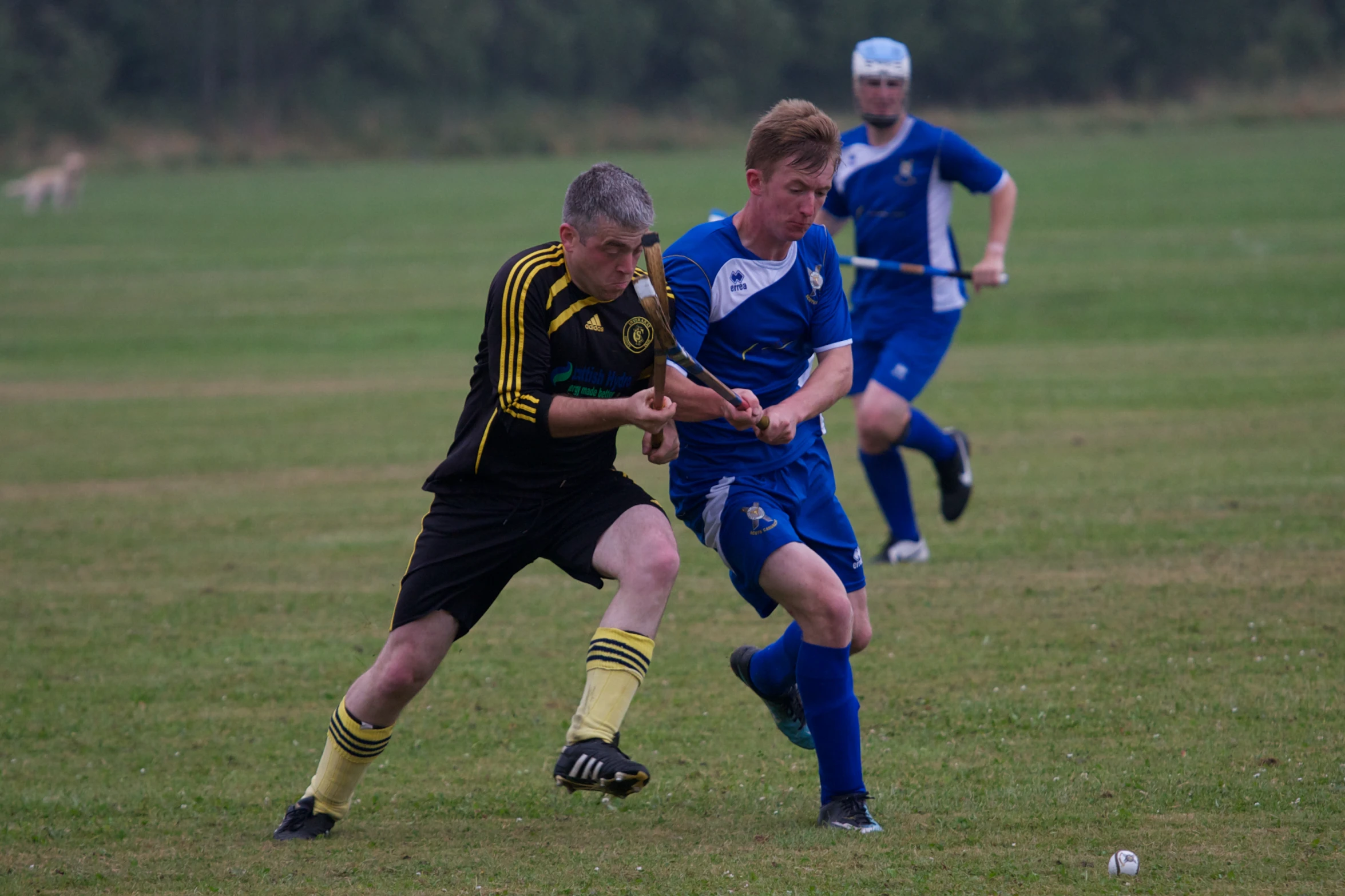 three boys playing soccer in the field, both with the ball and one with the ball