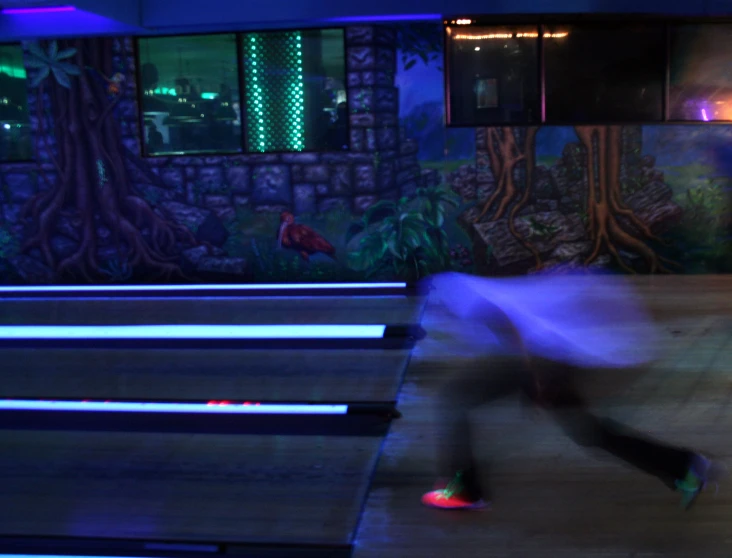 the motion blurs an image of a man in a bowling alley