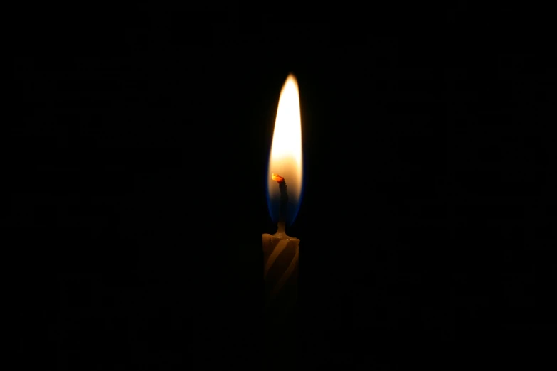 a small candle sitting alone on a dark table