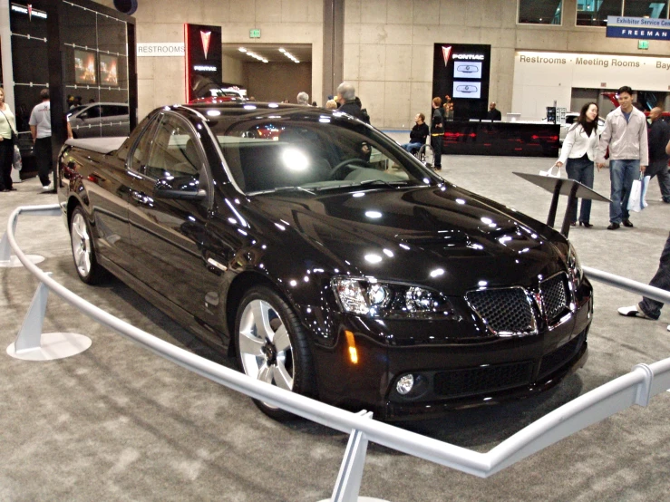 a black car parked on a lot near some people