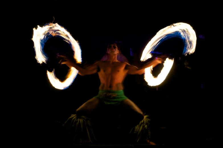 a man is doing aerial circus with fire circles